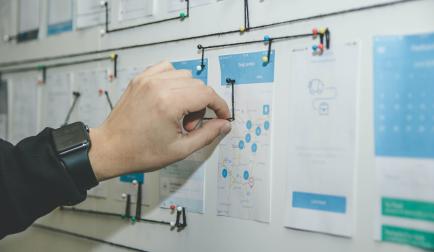 Käsi pyörittää lankaa seinässä olevan nastan ympärille